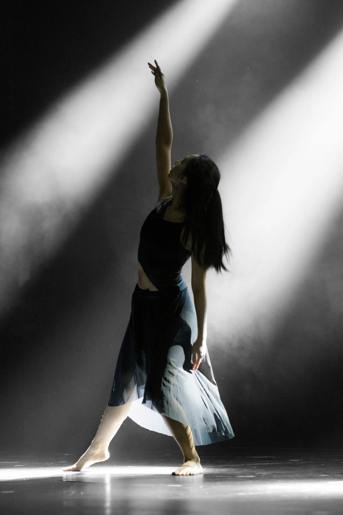 Person dancing in a beam of light on a dark stage