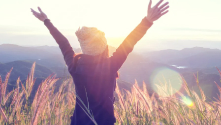 Person raising arms towards the sky in nature at sunset
